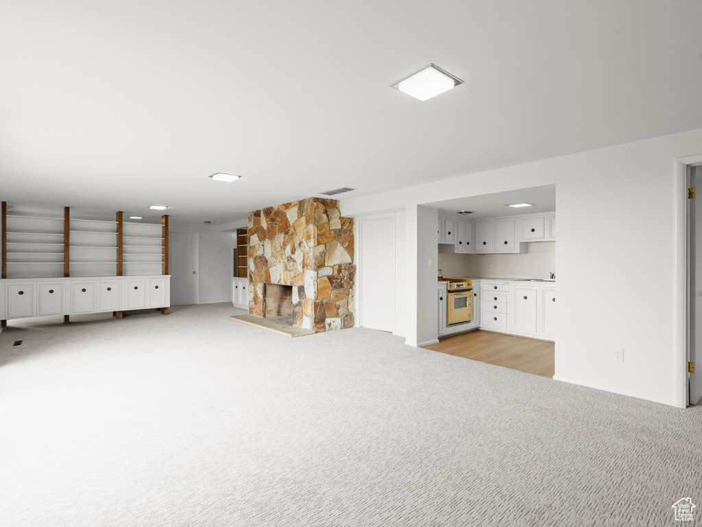 Unfurnished living room with light carpet and a fireplace