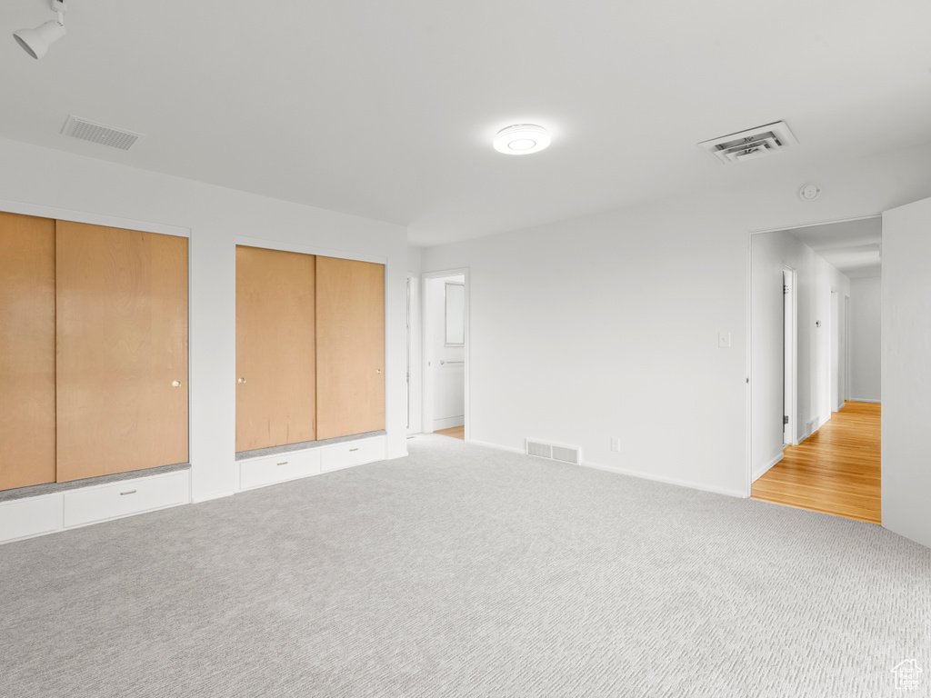 Unfurnished bedroom featuring multiple closets and light carpet