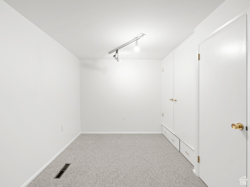 Carpeted spare room with baseboards and track lighting