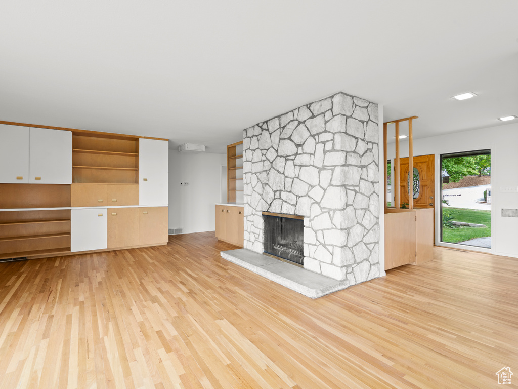 Unfurnished living room with wood finished floors and a stone fireplace