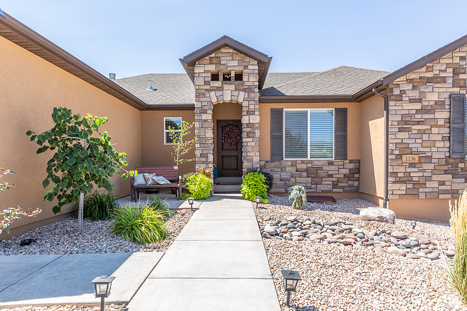Doorway to property with stucco siding, stone siding, and roof with shingles