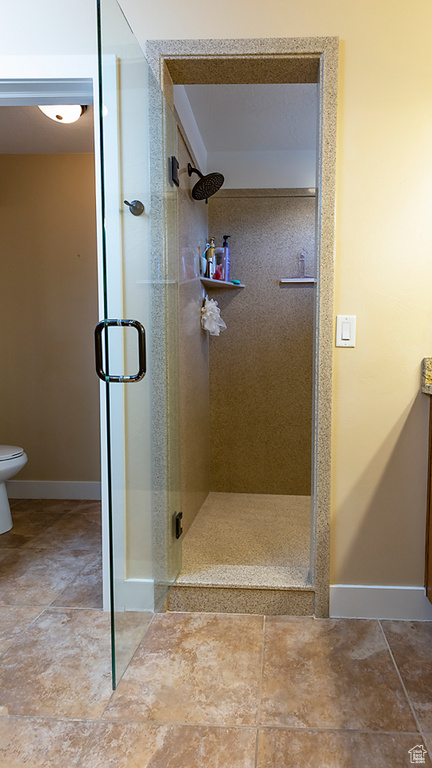 Full bath with a stall shower, baseboards, and toilet