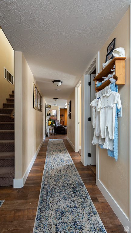 Hall with stairway, baseboards, dark wood-style flooring, and a textured ceiling