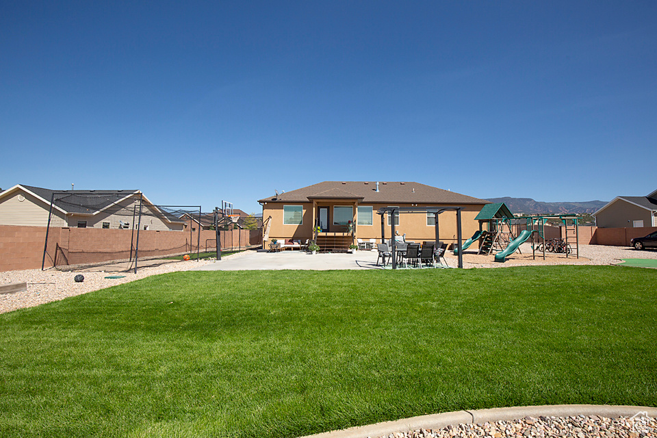 Back of house featuring a playground, entry steps, and a patio
