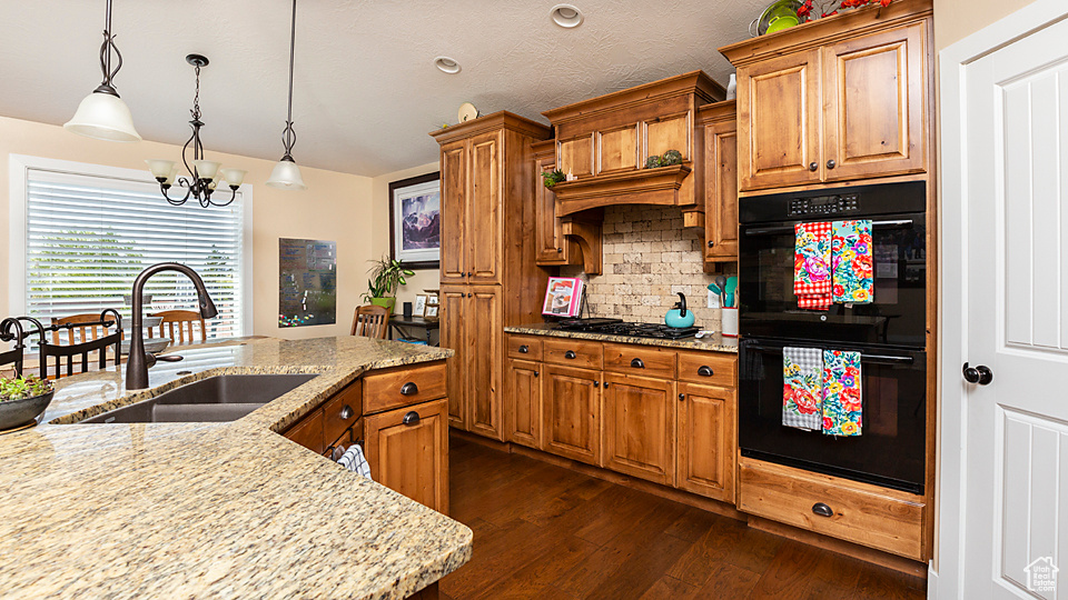 Kitchen featuring a sink, brown cabinetry, a chandelier, and tasteful backsplash