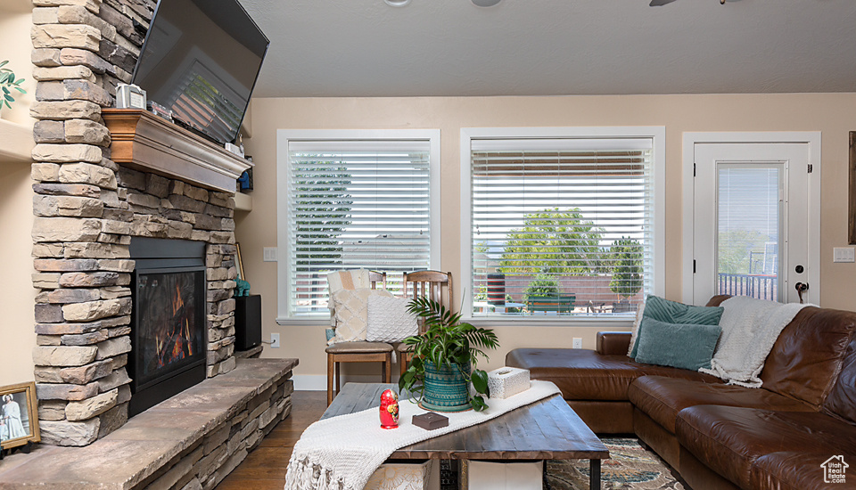 Living area with a stone fireplace, dark wood-style flooring, and baseboards