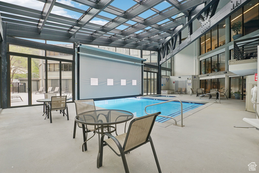 Indoor pool with a pergola, a hot tub, a patio, and outdoor dining area