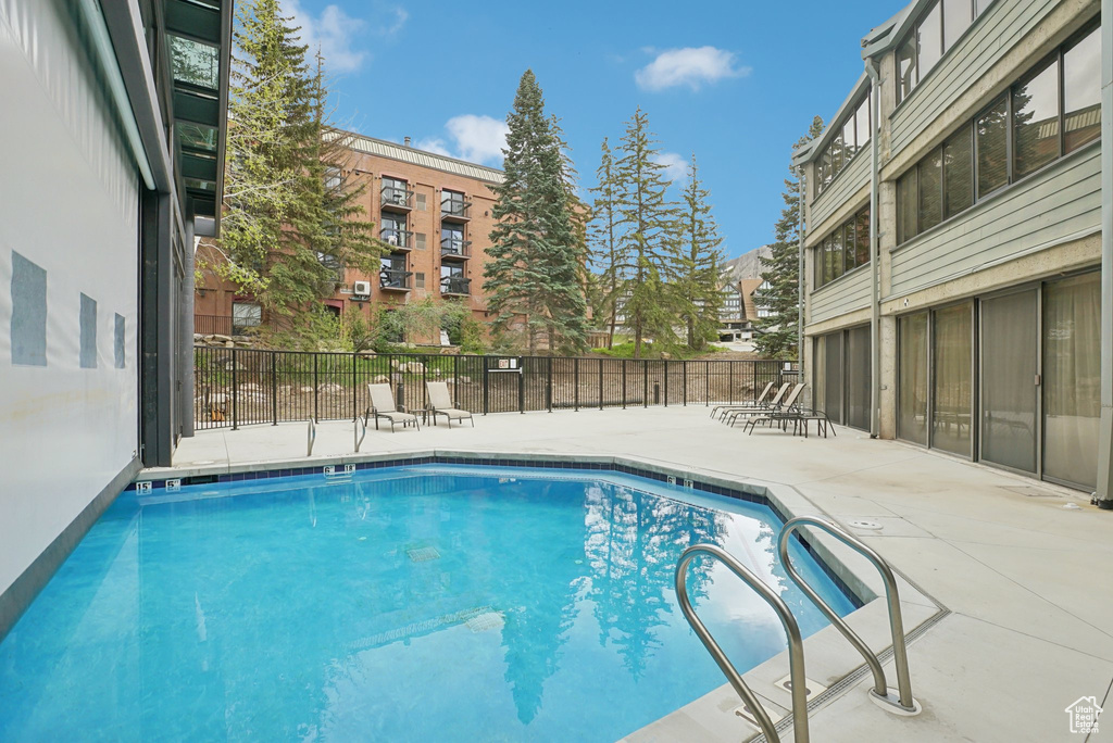 Community pool featuring a patio and fence