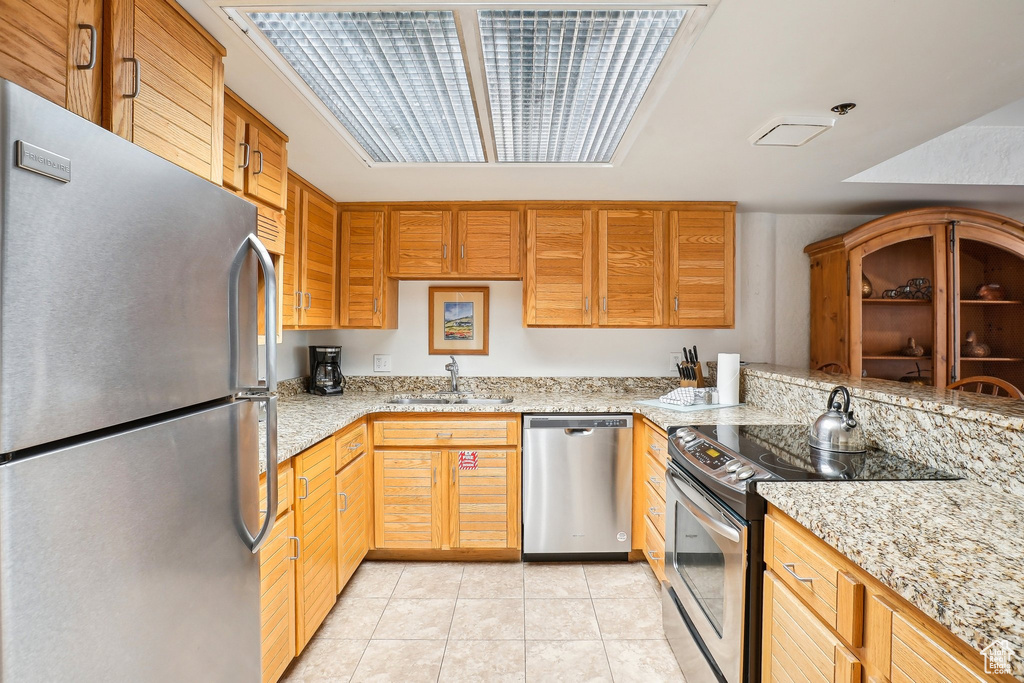 Kitchen featuring appliances with stainless steel finishes, a sink, and light tile patterned floors