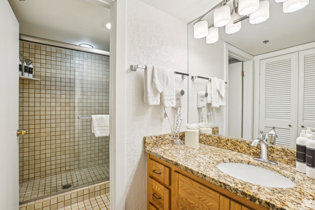 Bathroom featuring a shower stall, vanity, and a textured wall