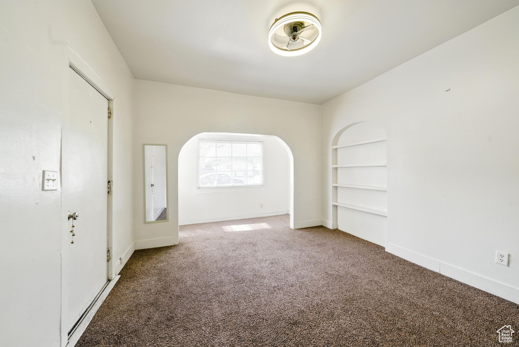 Unfurnished room featuring carpet floors, baseboards, and built in shelves