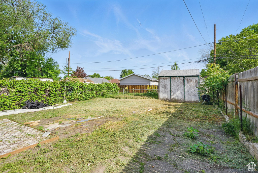Fenced backyard featuring a shed and an outbuilding