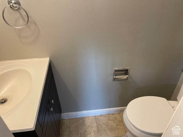 Bathroom with baseboards, vanity, tile patterned flooring, and toilet