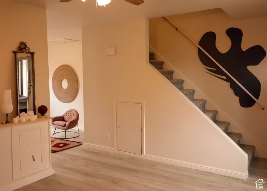 Stairway featuring ceiling fan, wood finished floors, and baseboards