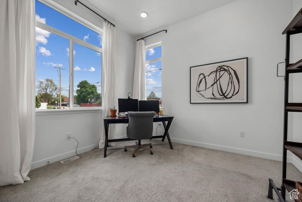 Carpeted office space with healthy amount of natural light and baseboards