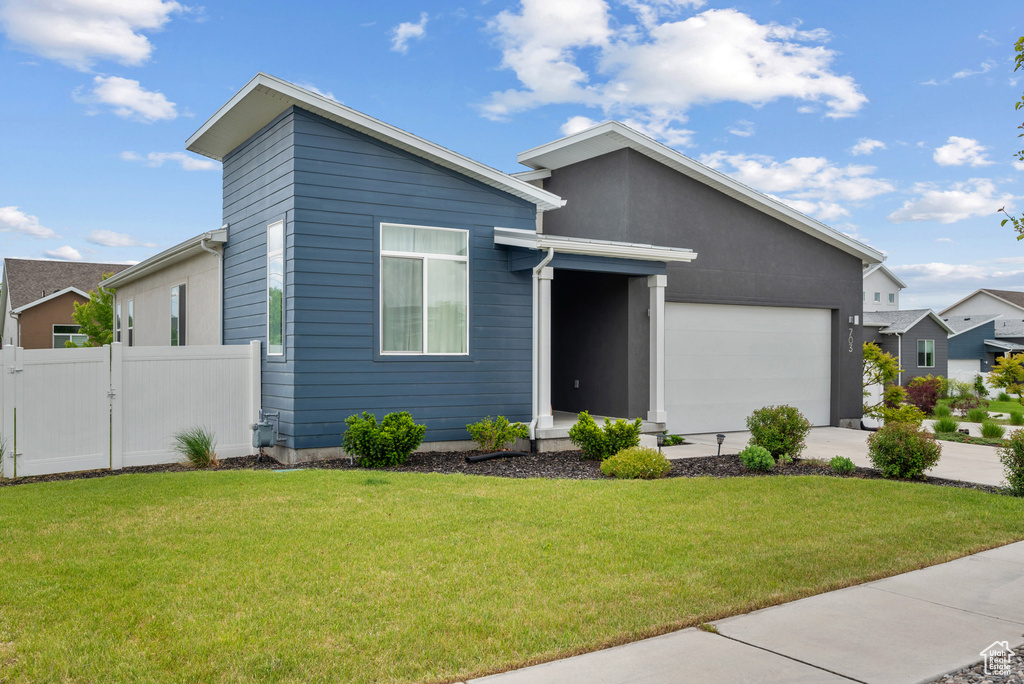 View of front of property with an attached garage, concrete driveway, and a gate