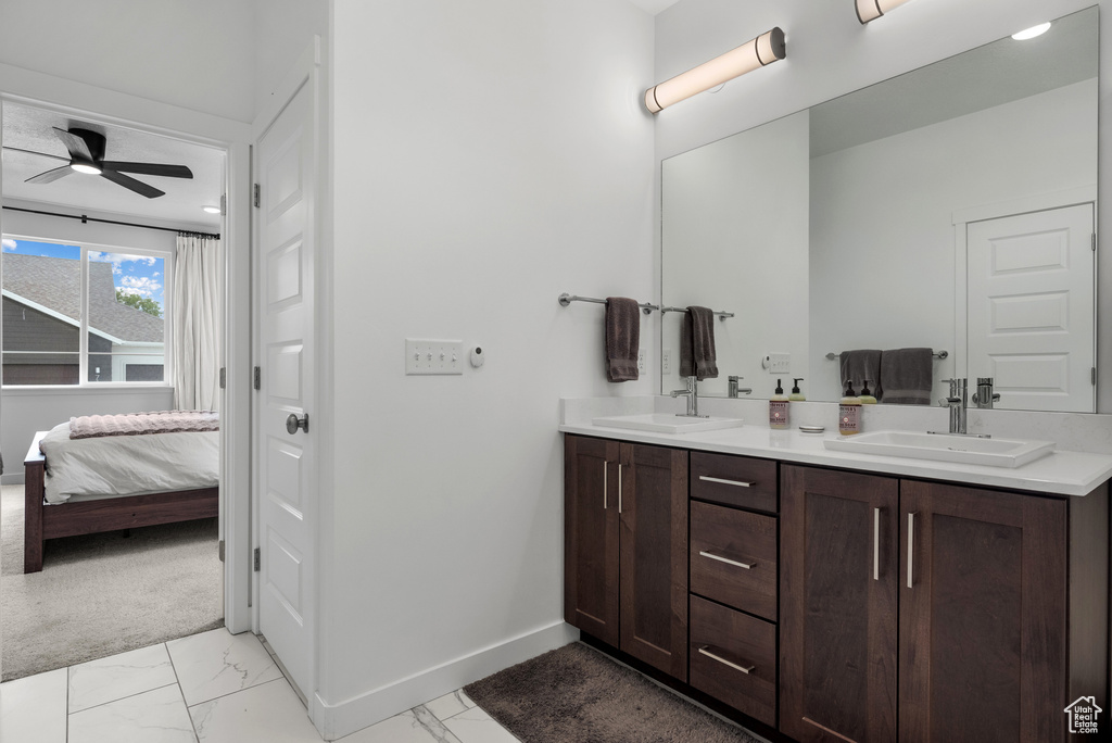Ensuite bathroom featuring marble finish flooring, a ceiling fan, baseboards, and double vanity
