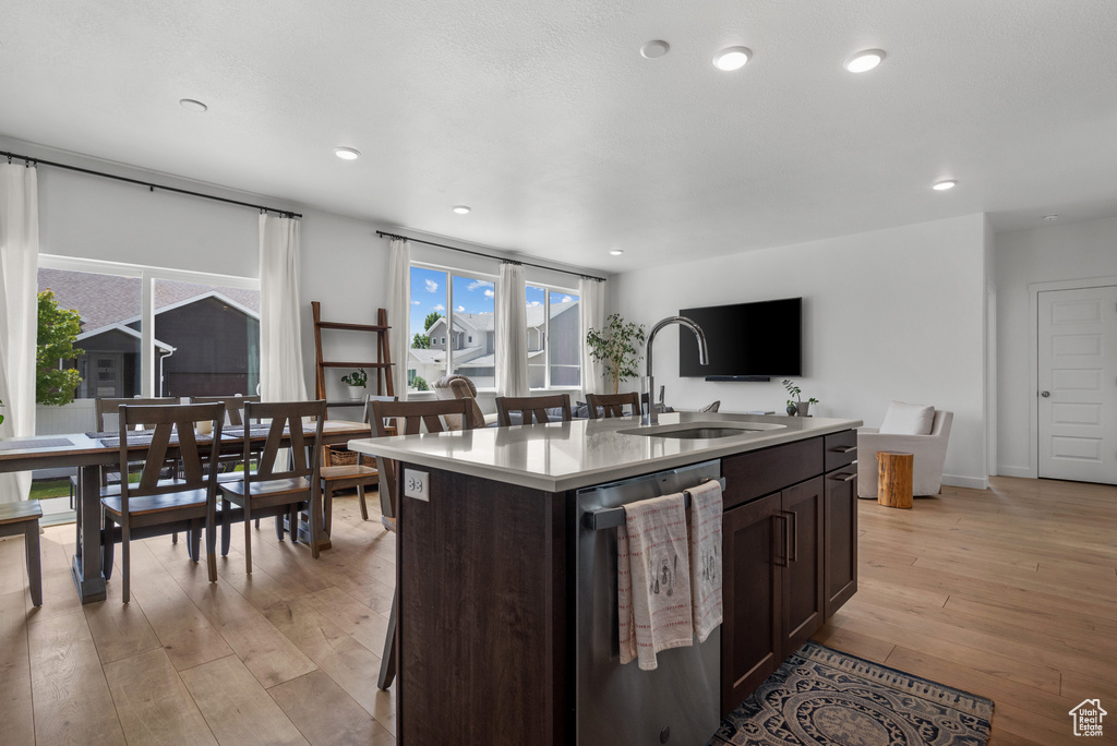 Kitchen featuring dishwasher, a sink, light wood-style flooring, dark brown cabinets, and light countertops