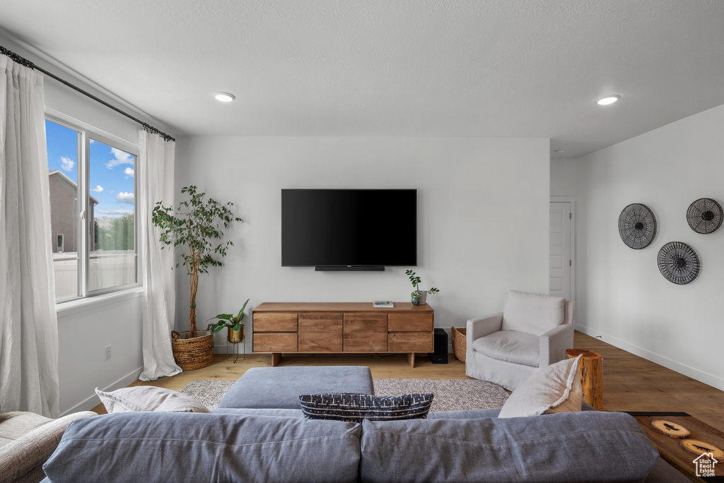 Living room with baseboards, light wood-type flooring, and recessed lighting