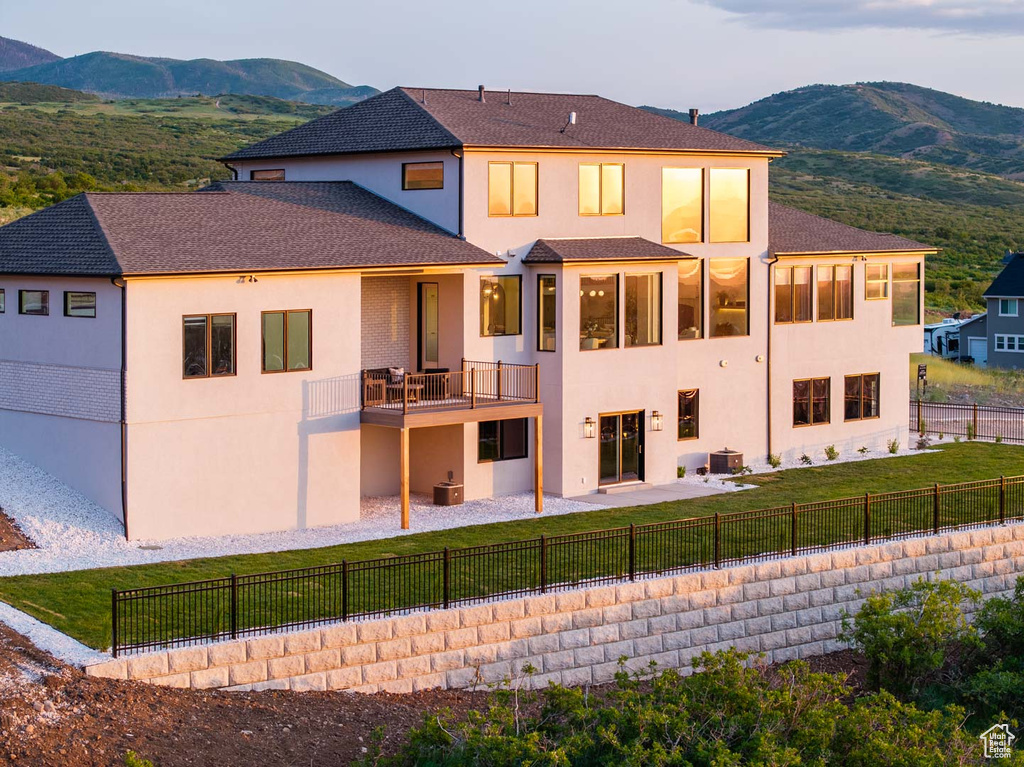 Back of house with a mountain view, stucco siding, a balcony, and a patio area