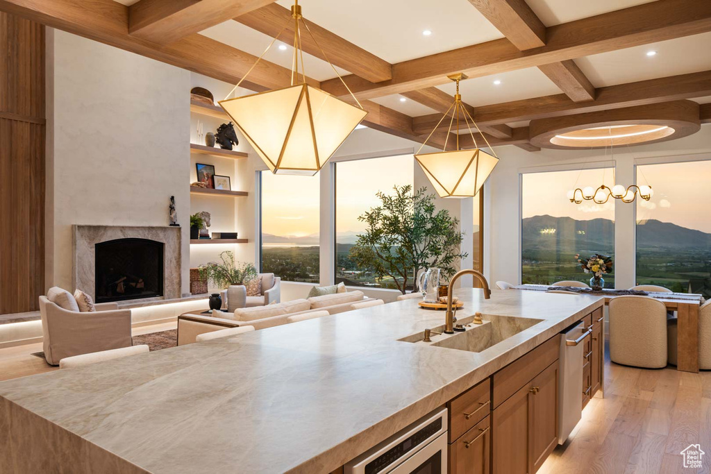 Kitchen with a sink, open floor plan, coffered ceiling, beam ceiling, and a fireplace with raised hearth