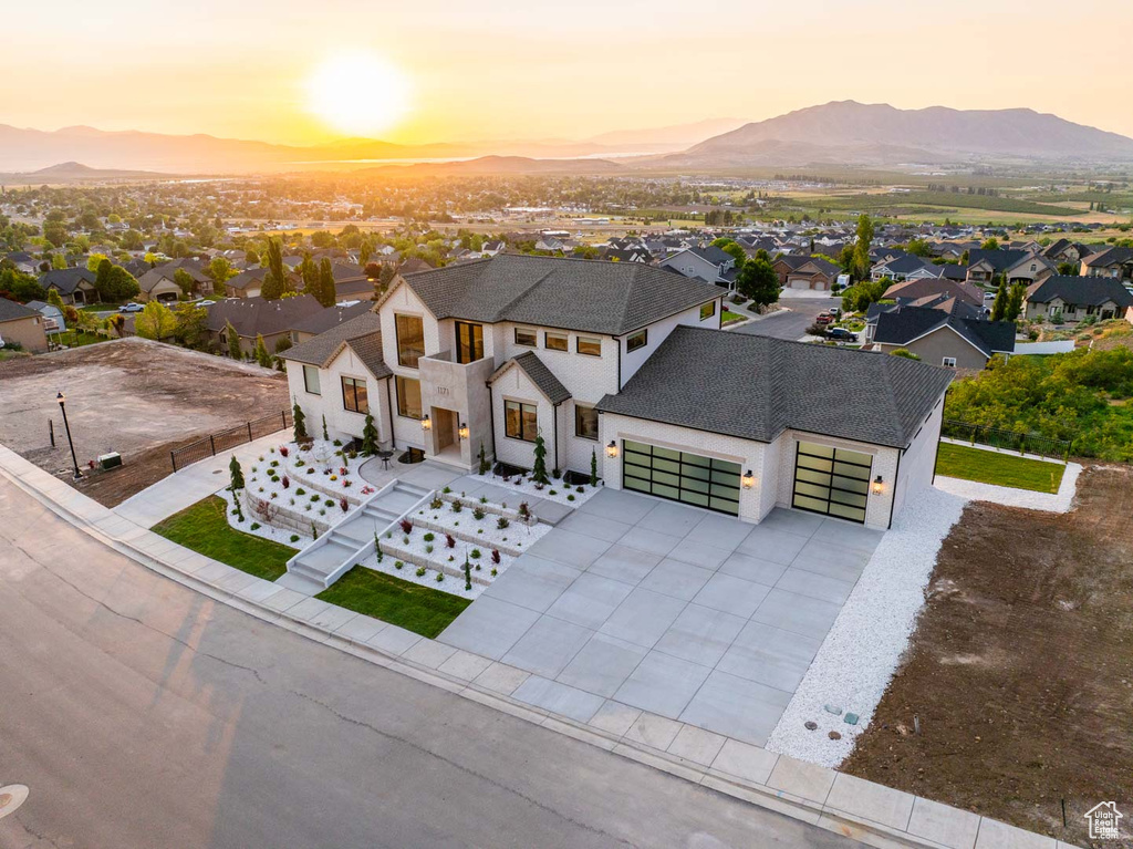 View of front of property with a mountain view, a garage, driveway, and a residential view