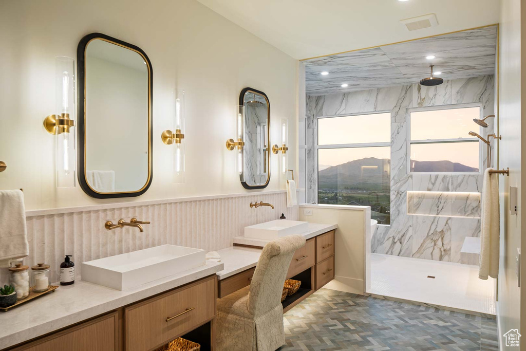 Full bathroom with double vanity, a marble finish shower, and wainscoting