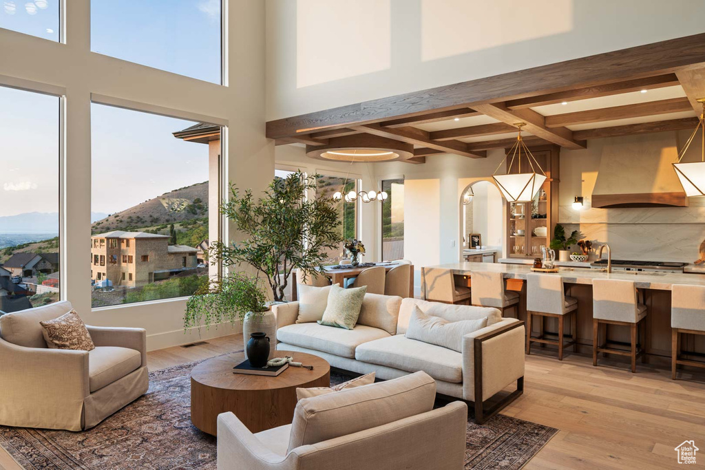 Living room with coffered ceiling, a mountain view, light wood-type flooring, beamed ceiling, and a chandelier