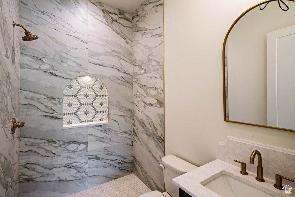 Bathroom featuring a marble finish shower, vanity, and toilet
