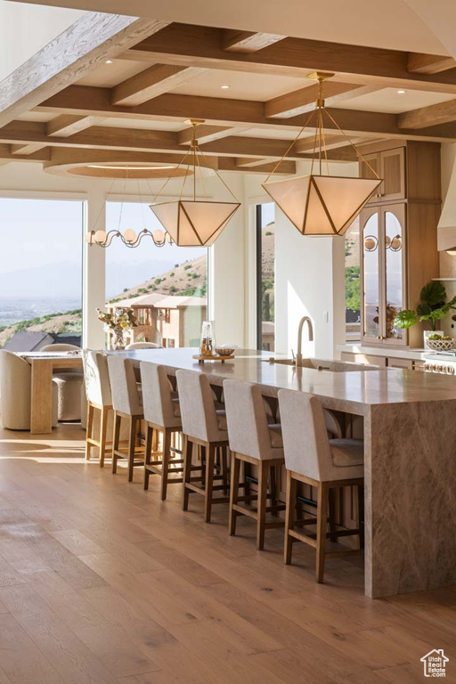 Kitchen featuring coffered ceiling, beam ceiling, wood finished floors, a sink, and a breakfast bar