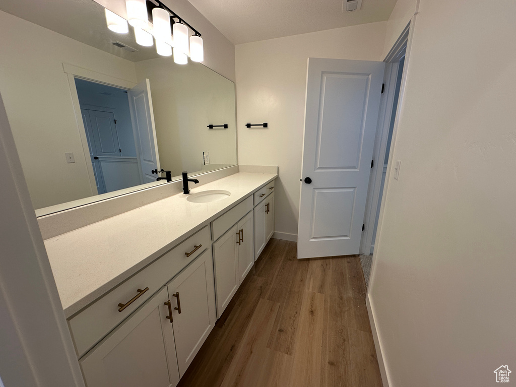 Bathroom with wood finished floors, vanity, and baseboards
