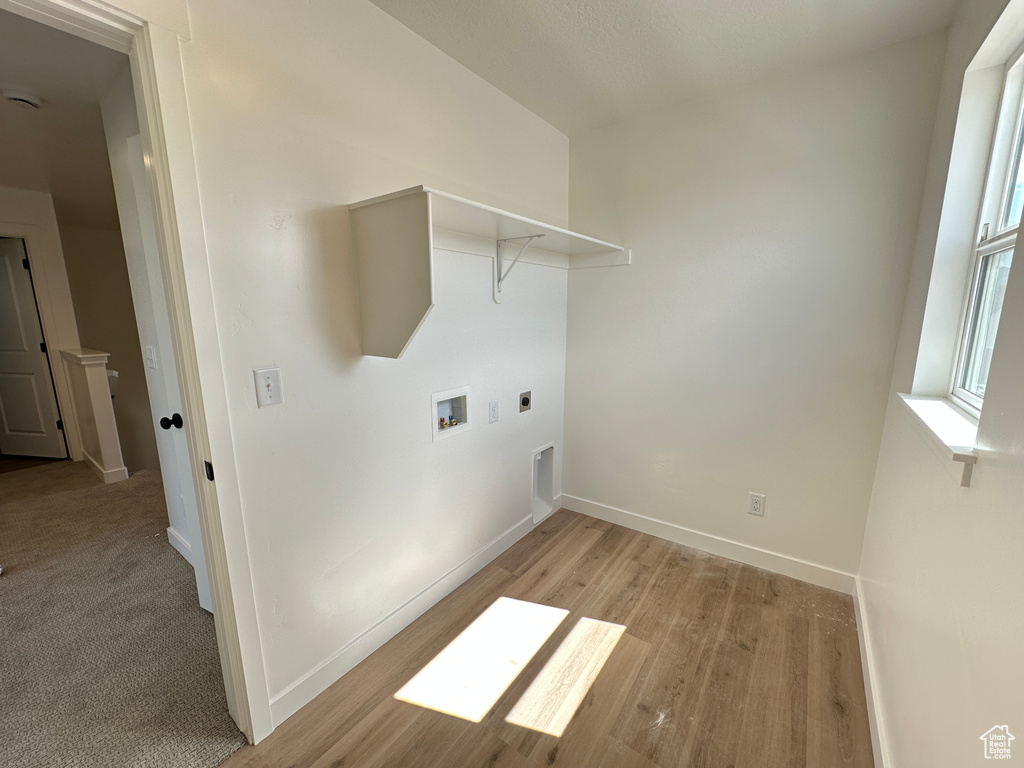 Laundry room featuring electric dryer hookup, hookup for a washing machine, baseboards, and light wood-style flooring