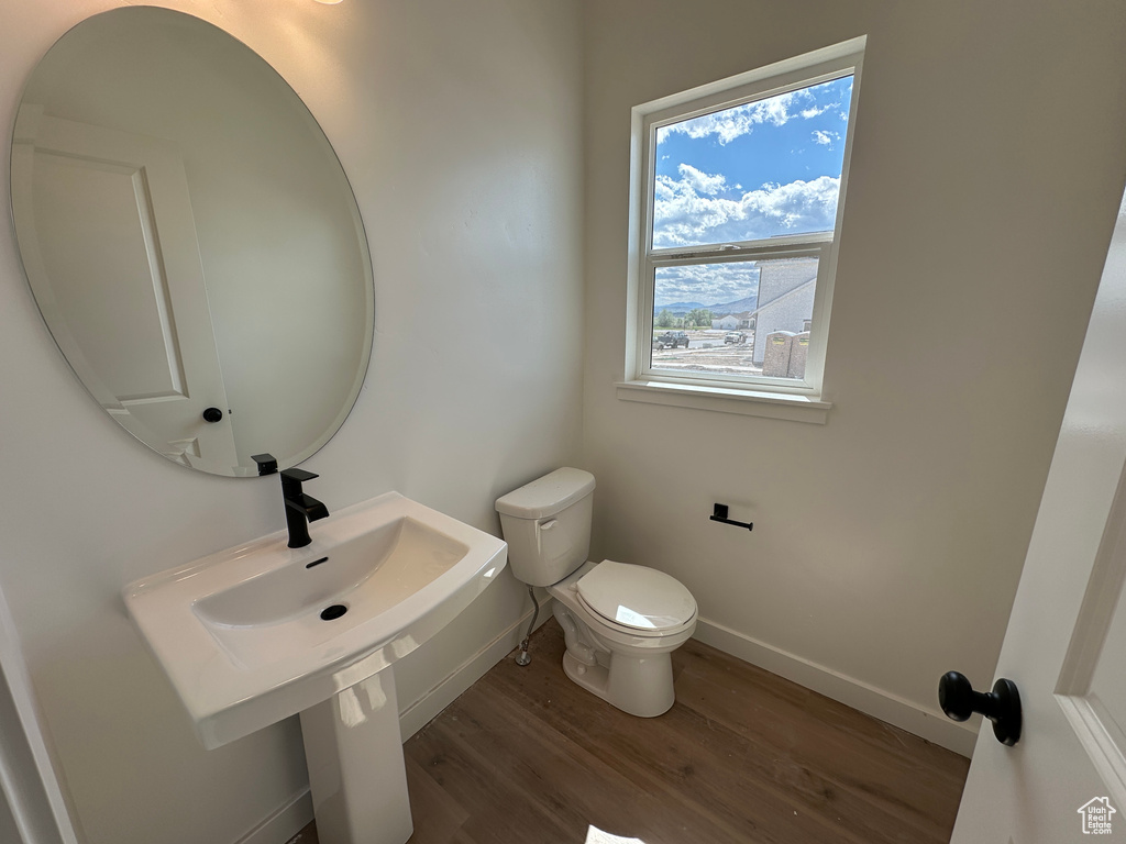 Half bathroom with wood finished floors, toilet, and baseboards