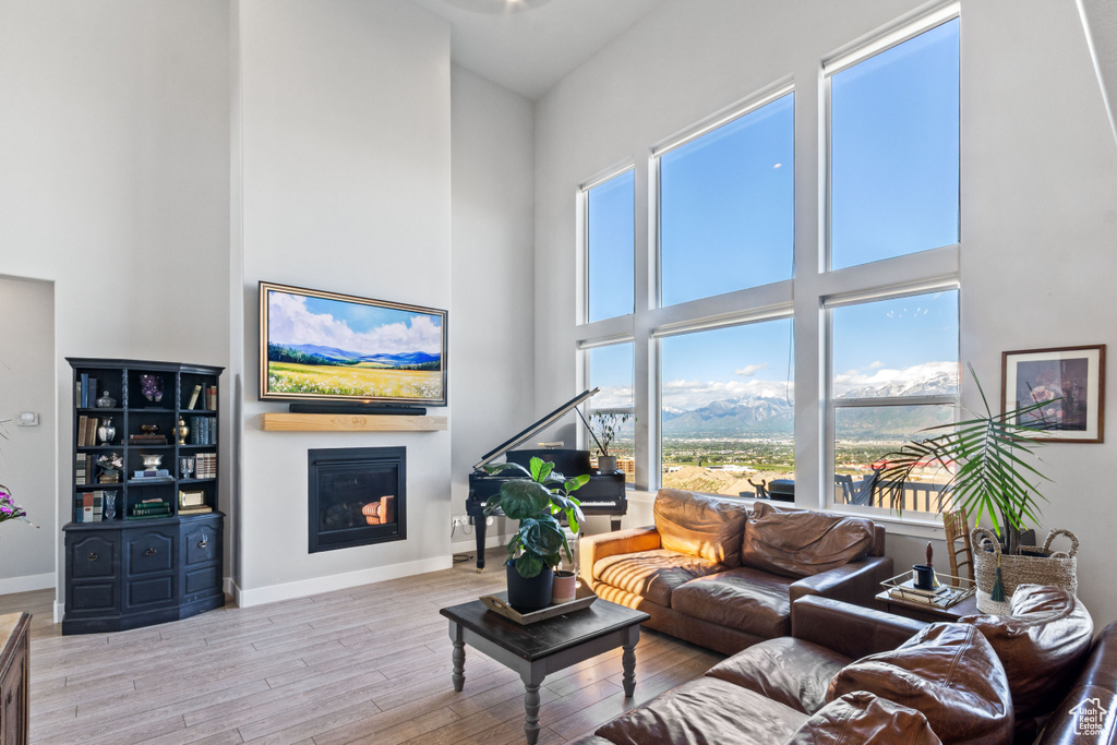 Living area with a towering ceiling, a glass covered fireplace, wood finished floors, and baseboards