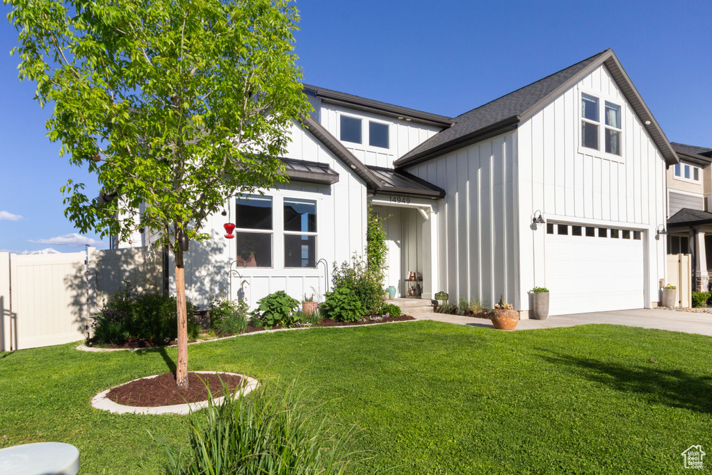 Modern farmhouse style home with board and batten siding, a standing seam roof, concrete driveway, metal roof, and a garage
