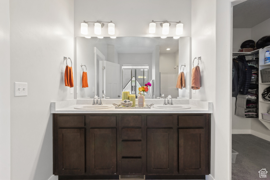 Full bath with double vanity, a spacious closet, and baseboards