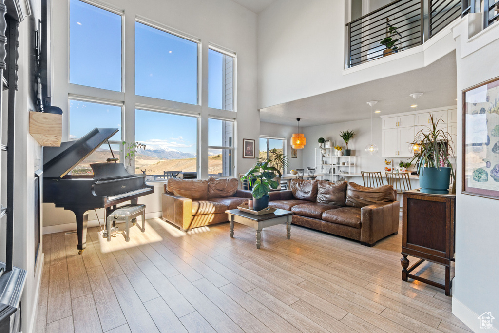 Living room with a high ceiling, light wood-style floors, and baseboards