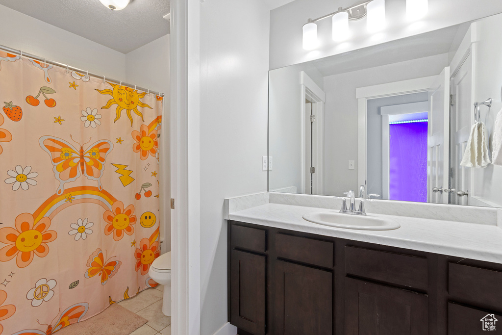 Bathroom featuring tile patterned flooring, vanity, toilet, and a shower with curtain