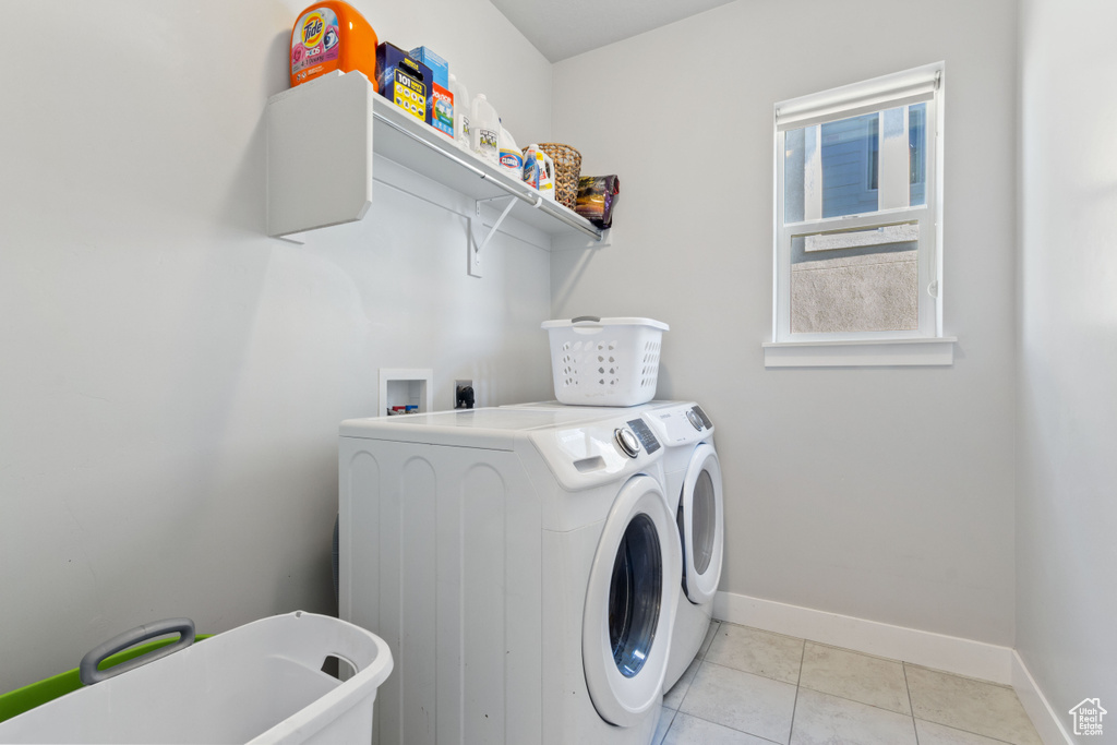 Washroom with independent washer and dryer, baseboards, and light tile patterned flooring