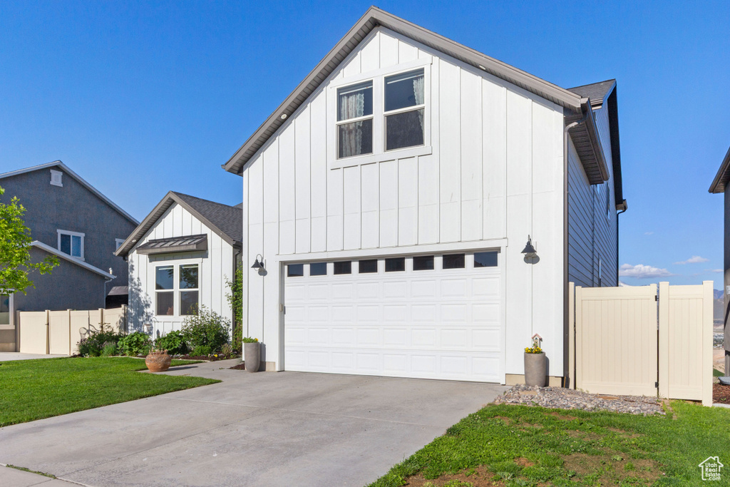 Modern farmhouse style home with board and batten siding, a garage, concrete driveway, and a standing seam roof