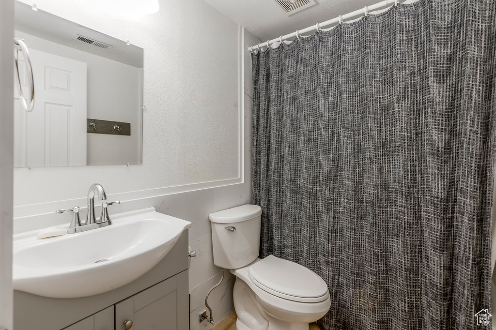 Full bathroom with vanity, toilet, and curtained shower
