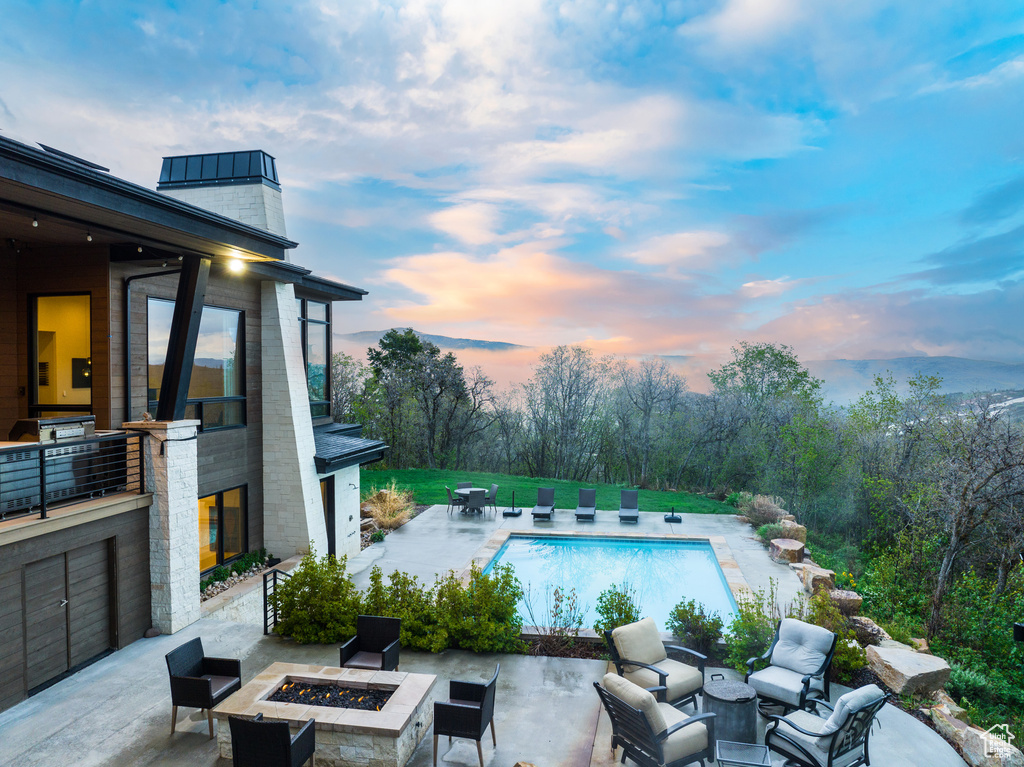 Outdoor pool featuring an outdoor fire pit and a patio