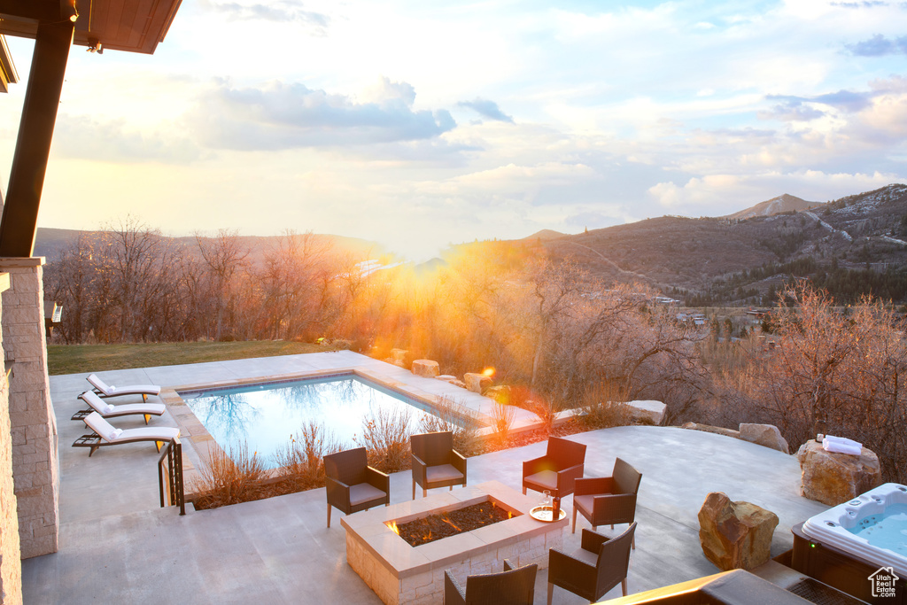 Swimming pool featuring an outdoor fire pit, a patio area, and a mountain view