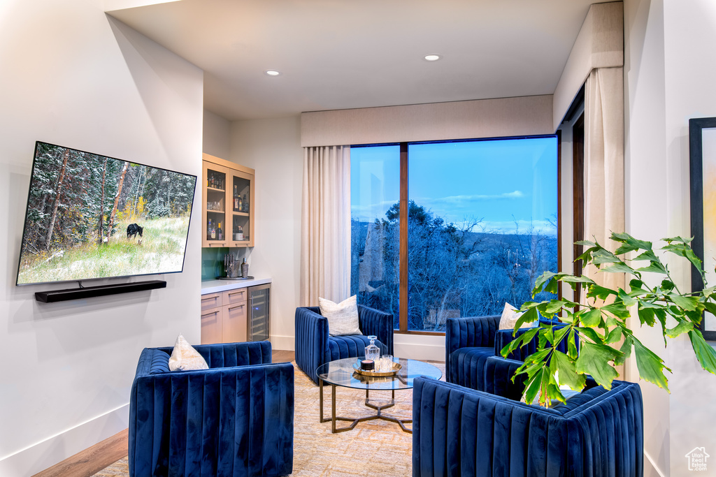 Living room featuring a bar, wine cooler, baseboards, wood finished floors, and recessed lighting