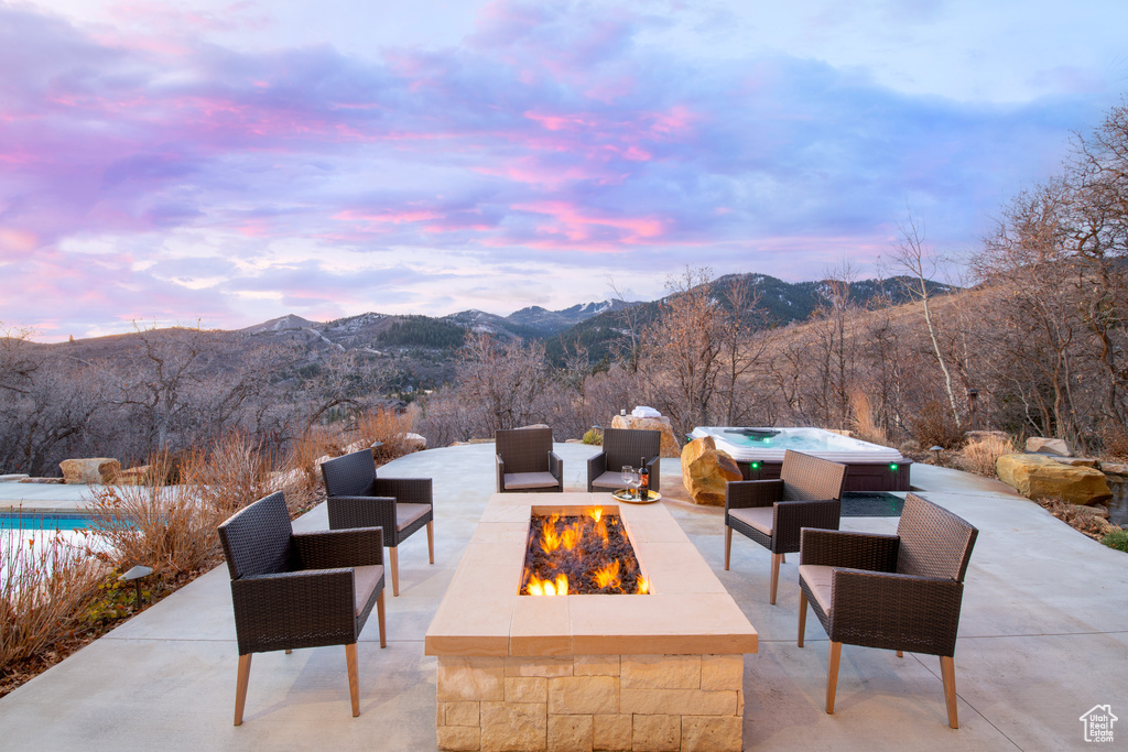 View of patio / terrace with a fire pit, a mountain view, and a jacuzzi
