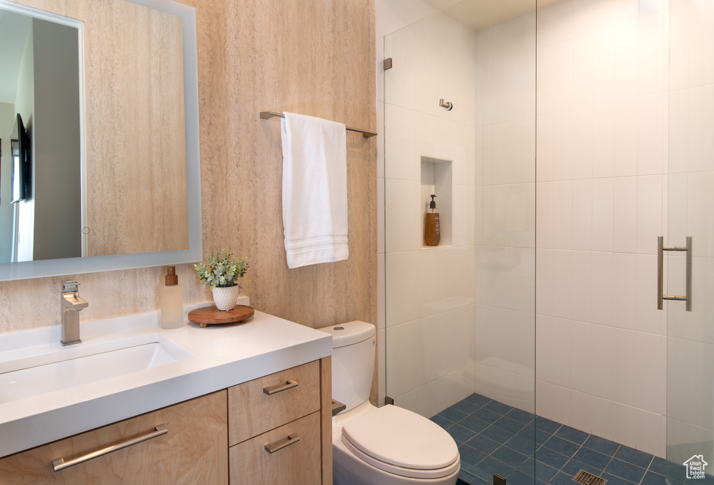 Bathroom featuring a shower stall, toilet, and vanity