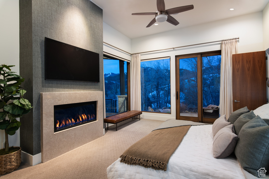 Carpeted bedroom featuring a glass covered fireplace, recessed lighting, access to outside, and a ceiling fan