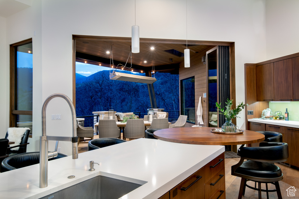 Kitchen with a sink, light countertops, modern cabinets, wooden walls, and brown cabinets
