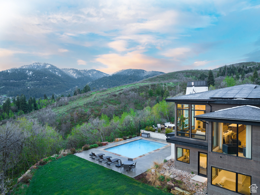 Swimming pool featuring a mountain view, a patio area, and a lawn