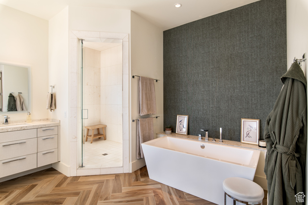 Bathroom featuring a stall shower, an accent wall, recessed lighting, a freestanding tub, and vanity